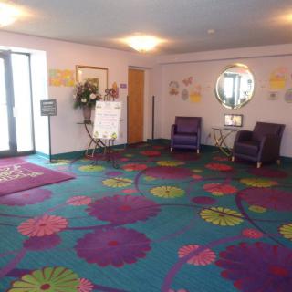 A brightly decorated lobby area with colorful floral carpeting, purple chairs, and a wall mirror.