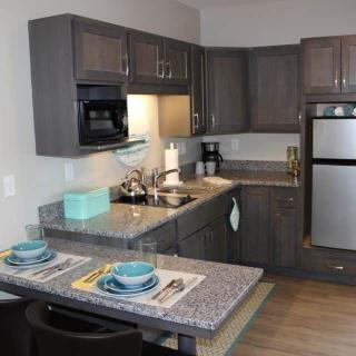 A modern kitchen with dark cabinetry and a small dining area.