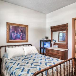 A cozy bedroom with vintage decor, featuring a quilt-covered bed and a wooden dresser with a mirror.