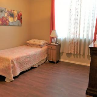 A cozy and minimalistic bedroom with a single bed, warm lighting, and decorative artwork.
