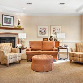 A cozy living room with a sofa and armchairs, featuring a fireplace and decorative elements.