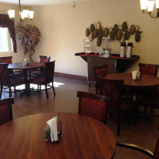 A cozy dining area with wooden tables and chairs, soft lighting, and decorative elements.