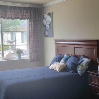 A cozy bedroom featuring a neatly made bed, decorative pillows, and a window with natural light.