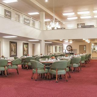 Spacious dining area with neatly arranged tables and chairs on a red carpet.