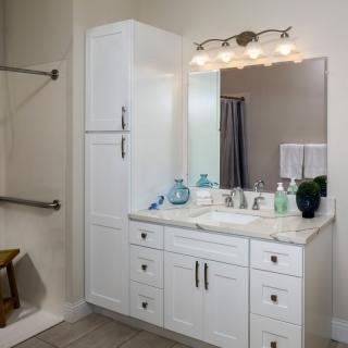A modern bathroom with a white vanity, mirror, and stylish lighting fixtures.