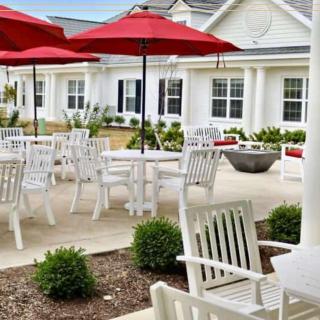 A well-maintained outdoor patio area with tables, chairs, and red umbrellas.