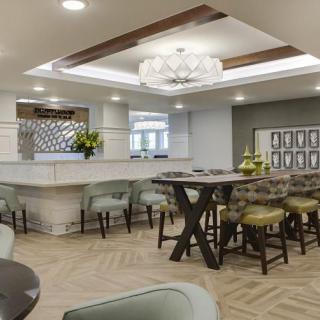 A modern kitchen and dining area featuring a central island, stylish bar stools, and a unique lighting fixture.