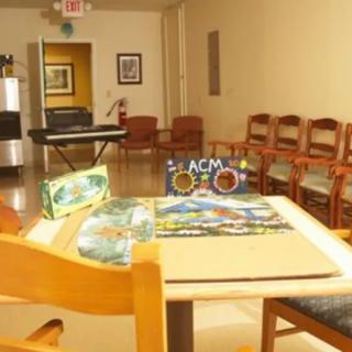A waiting room with arranged chairs, a table displaying puzzles and magazines.