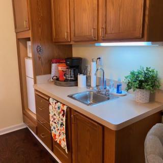A small kitchen area featuring a sink, wooden cabinets, and various appliances.