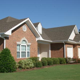 A suburban brick house with a well-maintained lawn and landscaped garden.