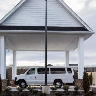 A white van parked under a sheltered structure with columns.