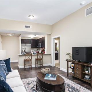 A modern living room with an open floor plan leading to the kitchen, featuring comfortable seating and stylish decor.