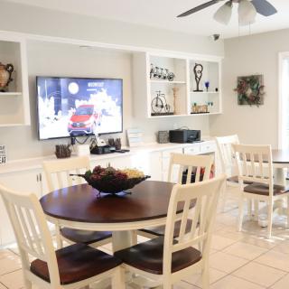 A cozy living room with a dining table, TV, and decorative shelves.