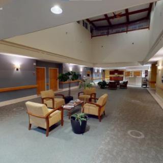 A modern lobby with comfortable seating and plants, featuring warm lighting and a spacious layout.