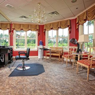 A stylish salon waiting area featuring comfortable seating, large windows with scenic views, and a modern chandelier.