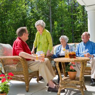 A cheerful gathering of friends enjoying drinks on a sunny porch.