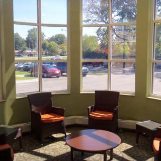 A well-lit waiting room with chairs and large windows.
