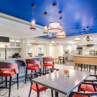 A modern restaurant interior with red chairs, a blue ceiling, and stylish lighting fixtures.