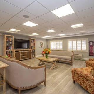 A cozy and well-lit living room featuring comfortable seating, decorative shelves, and a touch of nature with flowers.