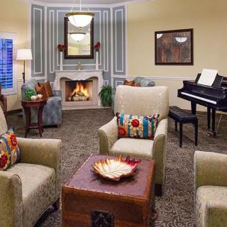 A cozy living room with a fireplace, comfortable armchairs, and a piano.