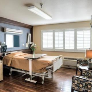 A well-lit hospital room with a bed, medical equipment, and comfortable furnishings.