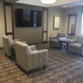 A cozy lounge area with comfortable chairs and a large television on the wall.