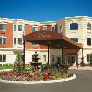 A hotel entrance with a landscaped garden and fountain.