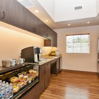 A modern kitchen area featuring a coffee station and snack selections, complemented by natural light.