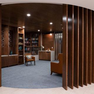 A modern library with wooden bookshelves and a cozy reading area.