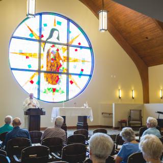 A serene moment during a service, featuring vibrant stained glass and an attentive congregation.