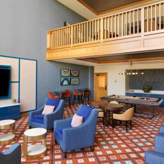 A modern lounge area with blue chairs, a loft, and stylish decor.