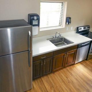A modern kitchen with stainless steel appliances and wood flooring.