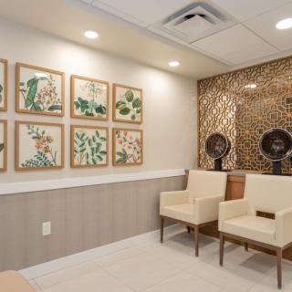 A well-designed waiting room with framed artwork and beige chairs.