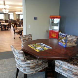 A cozy dining area featuring a round table with comfortable chairs and a vintage popcorn machine.