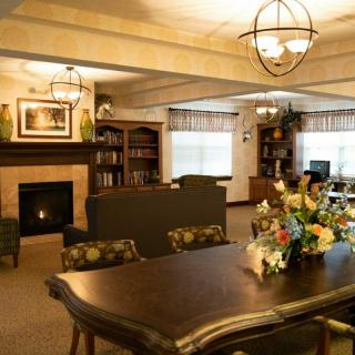 A cozy living room with a fireplace, bookshelves, and a dining table decorated with flowers.