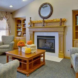 A cozy living room with a fireplace adorned with autumn decorations.