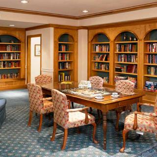 A cozy library reading room with bookshelves, a table, and chairs.