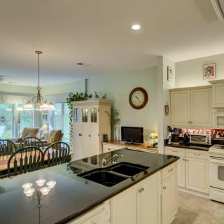 A modern open-concept kitchen with a granite island overlooking a cozy living and dining area.