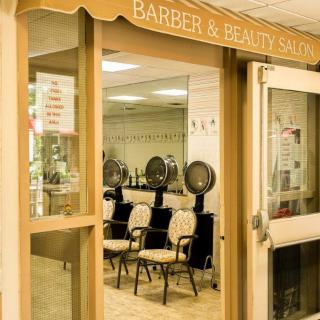 Entrance to a barber and beauty salon with chairs and hair dryers visible inside.