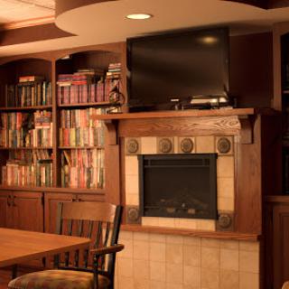 A warm and inviting living room featuring a fireplace, bookshelves filled with books, and a television.