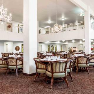 A spacious and elegant dining room featuring chandeliers and arranged tables and chairs.