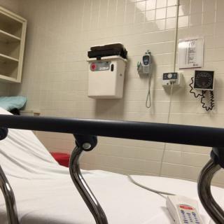 A hospital room with a bed and medical equipment on the wall.