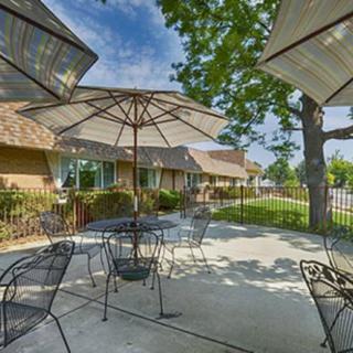 A cozy outdoor patio area with tables, chairs, and large umbrellas on a sunny day.