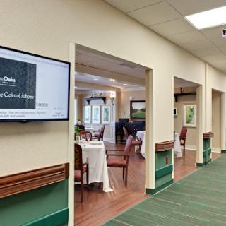 A view of a dining area featuring tables and chairs, with a television screen on the wall.