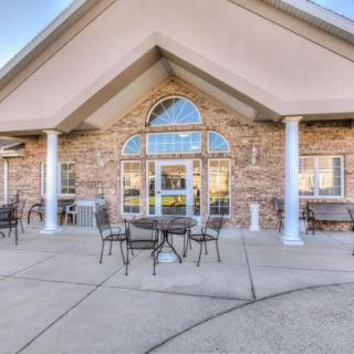A building entrance with a patio featuring outdoor furniture and columns.