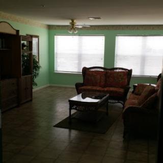 A spacious living room featuring a cozy seating area with a green color scheme.