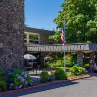 A building entrance with an American flag, surrounded by lush greenery and flowers.