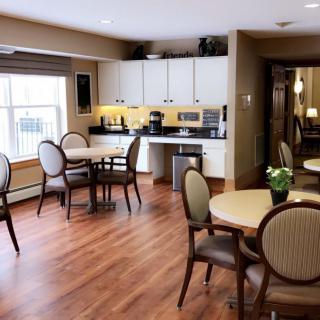 A modern kitchen and dining area featuring hardwood floors, tables, chairs, and appliances.