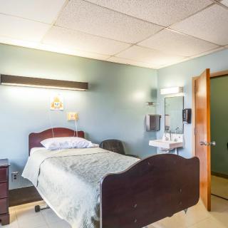 A clean and well-lit hospital room with a bed and essential furnishings.
