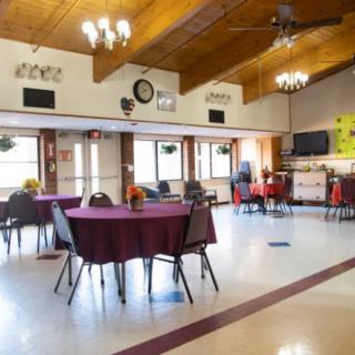 An empty dining hall with decorated tables and chairs, ideal for community gatherings.